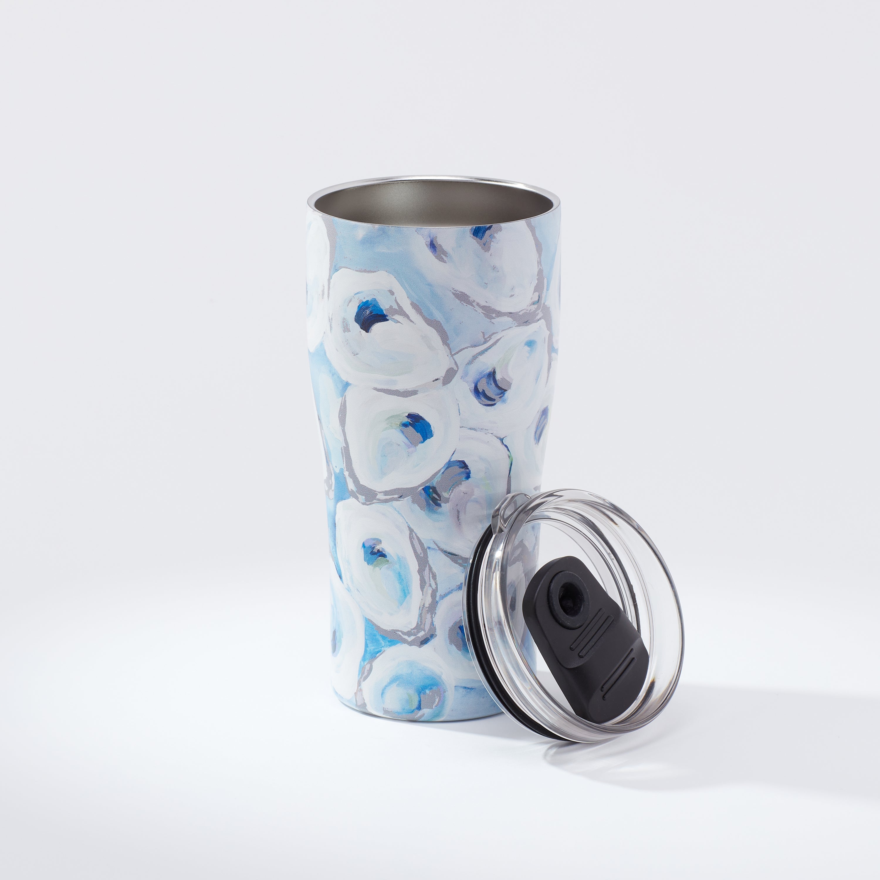 A blue and white oyster patterned 20oz coffee tumbler with a removable lid, displaying the 'Ebb and Flow' artwork.