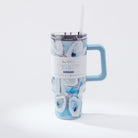 A blue and white oyster pattern 40oz tumbler with a handle and a straw, against a white background. Around tumbler features a package info sleeve. 