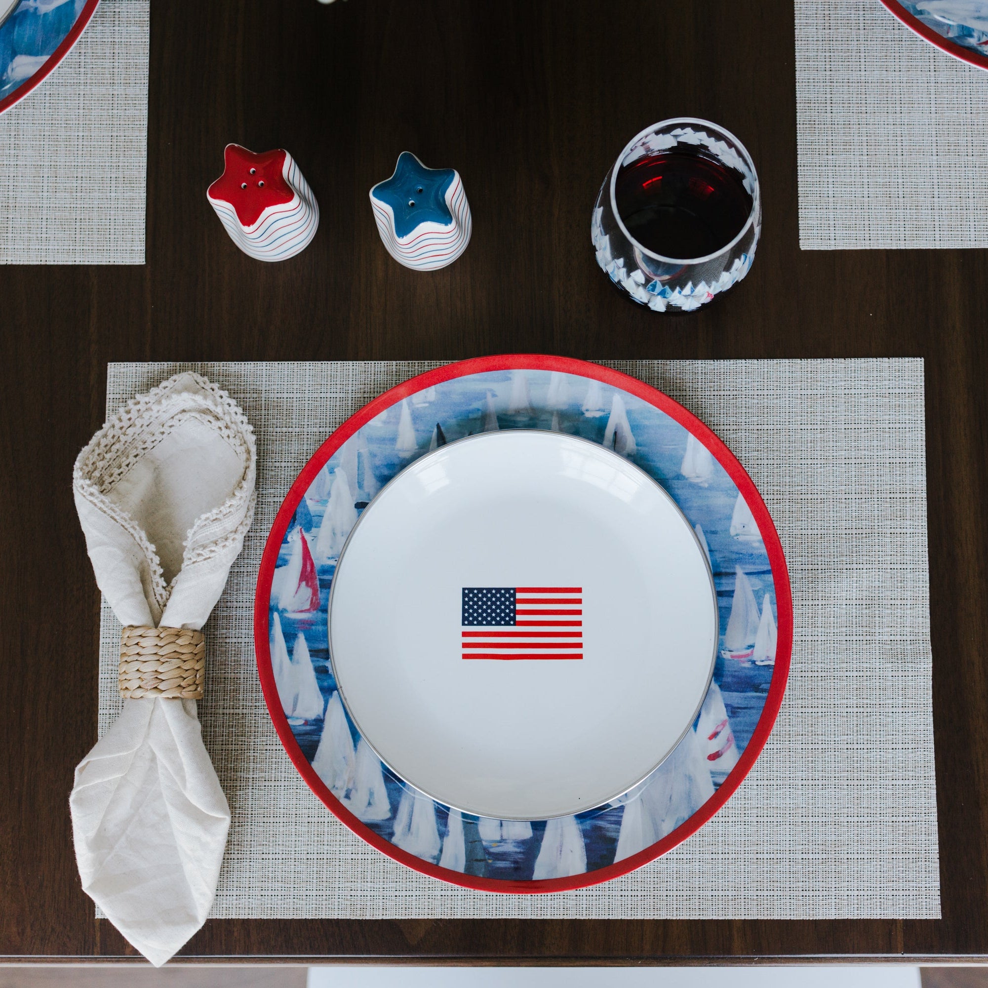 Dining table setting with a plate featuring an American flag, surrounded by placemats and cutlery.