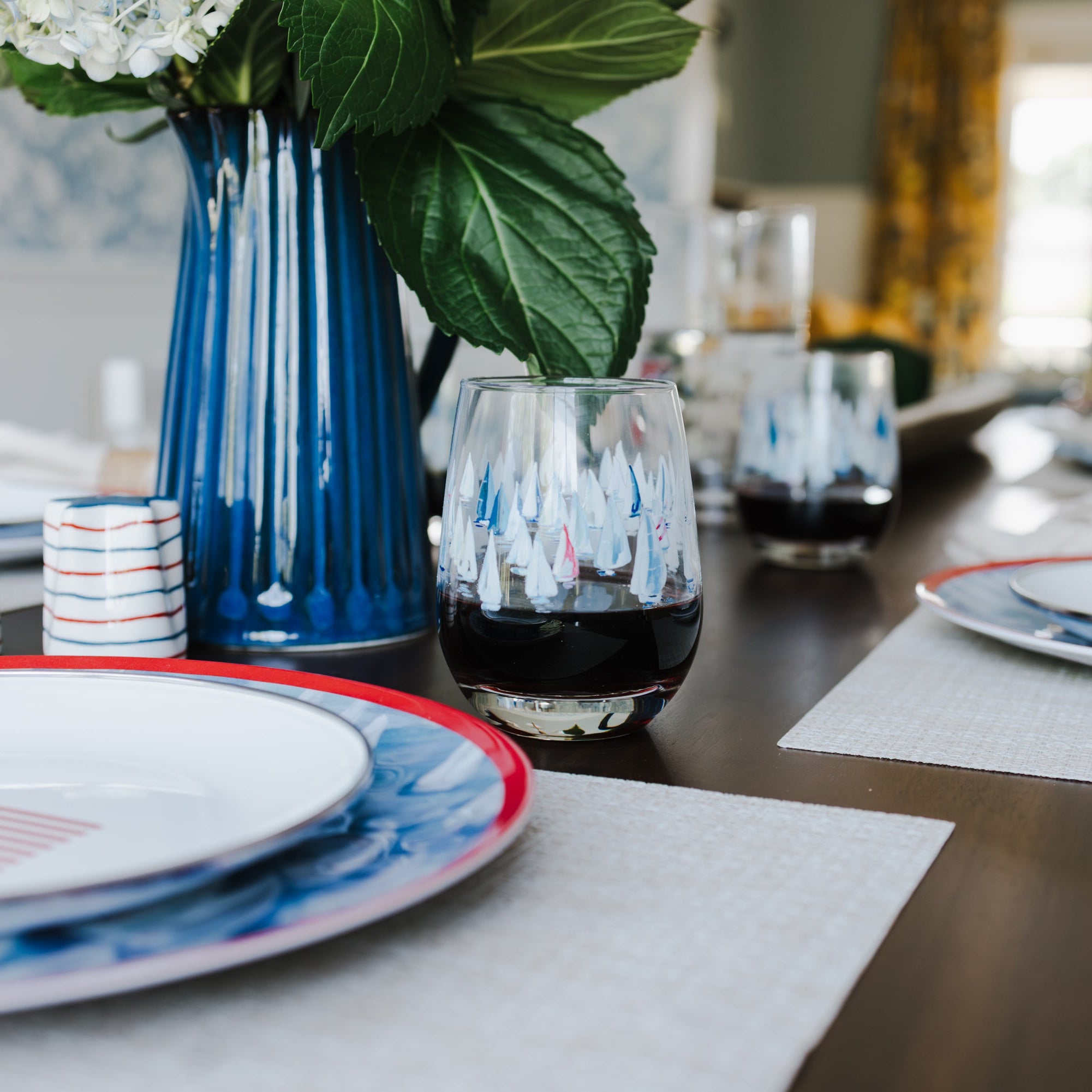Dining table set with plates, glasses, and a vase with flowers.