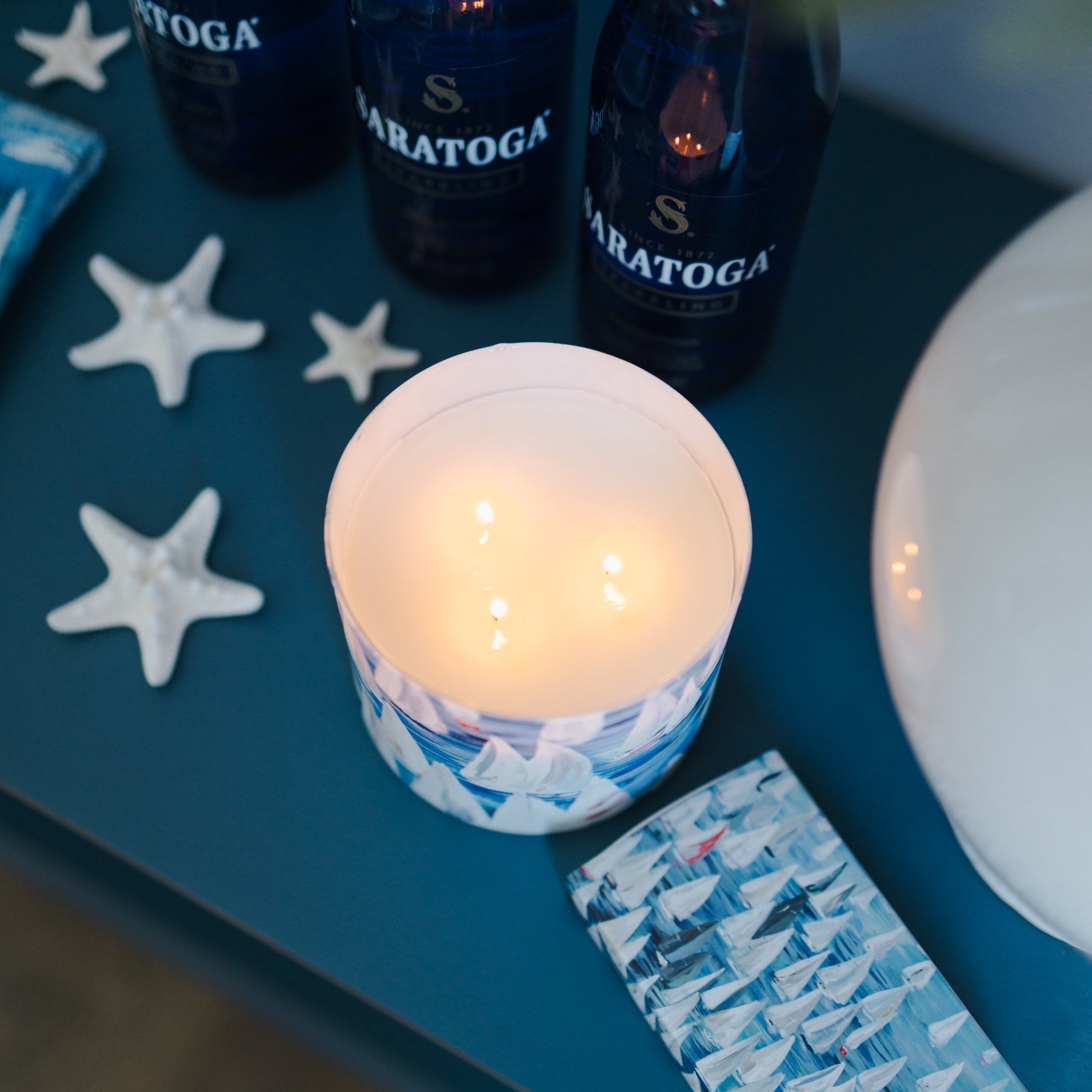 Nautical Sailboat Candle with starfish decorations on a blue surface