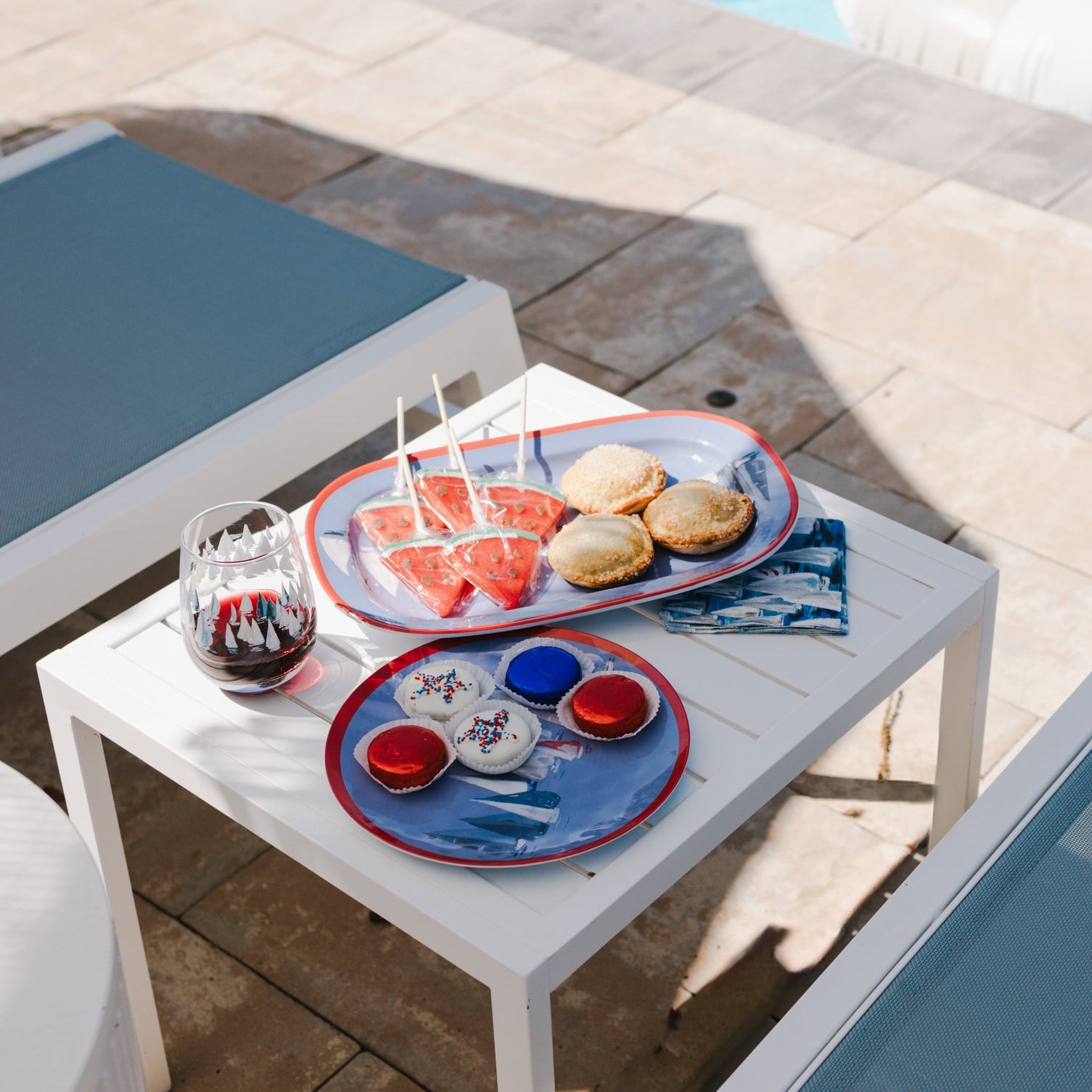 Outdoor setting with a table by a poolside featuring snacks and drinks.