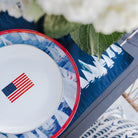 Sailboat table setting with a plate featuring an American flag, surrounded by white hydrangeas.