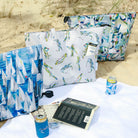 Collection of beach items designed by Kim Hovell on the sand with books and sunglasses. 