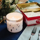 Candle with decorative design on a table with cutlery and a vintage-style box.
