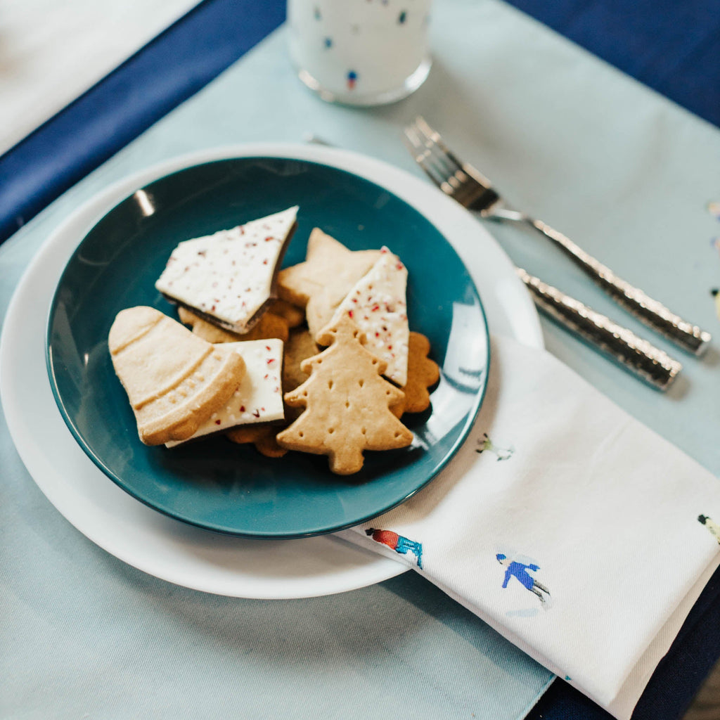 Plate of cookies with a glass of milk on a table with a blue placemat.