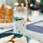 Glass mug with Christmas design on a table with cookies and cake
