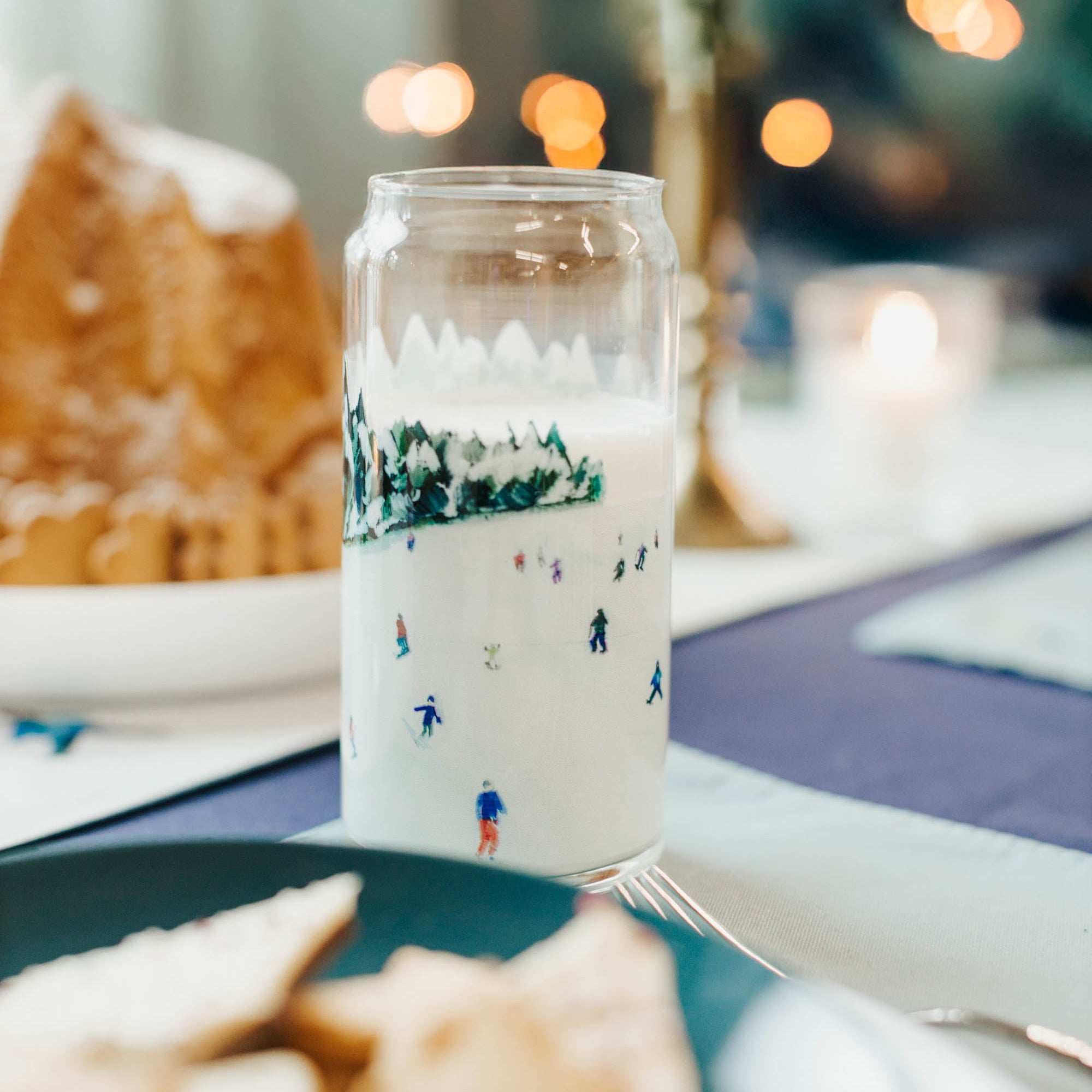 Glass mug with Christmas design on a table with cookies and cake