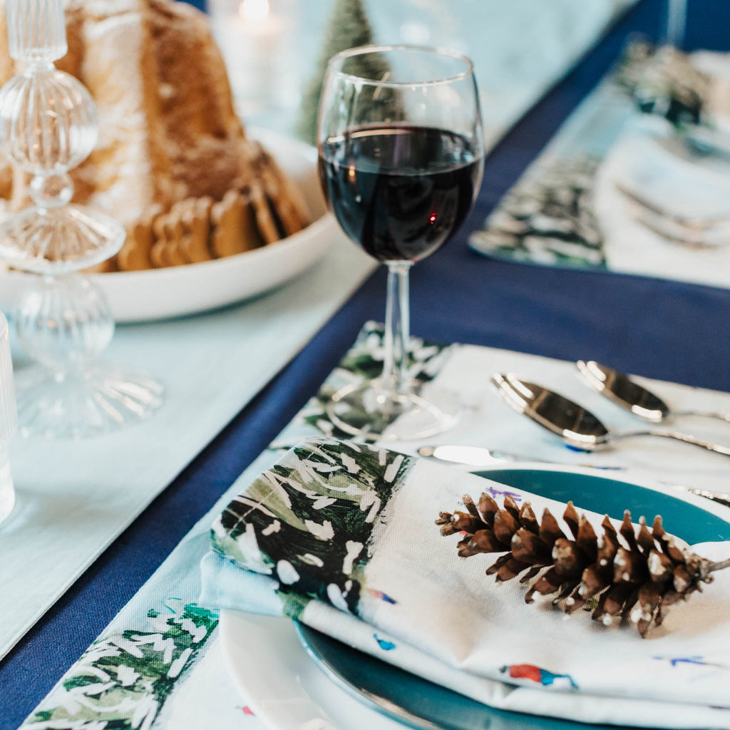 Dining table setting with wine glass, plates, and decorative elements on a blue tablecloth.