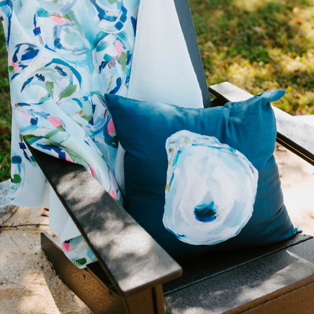 Chair with a colorful blanket and blue shell pillow on a grassy background