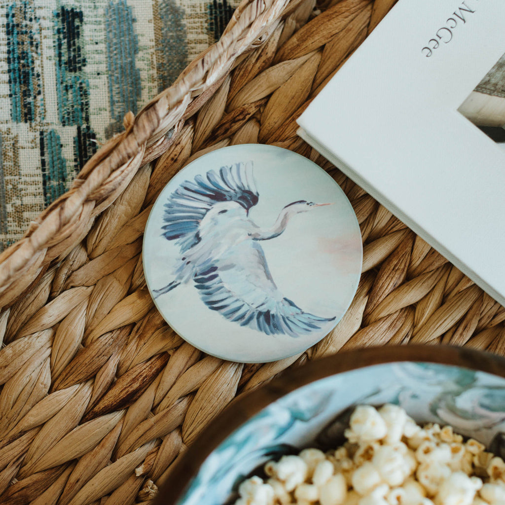 Coaster with bird design on woven mat with bowl of popcorn