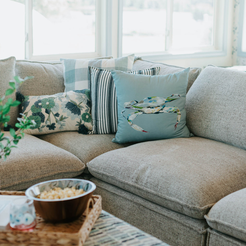 Gray sectional sofa with decorative pillows in a bright room with large windows.
