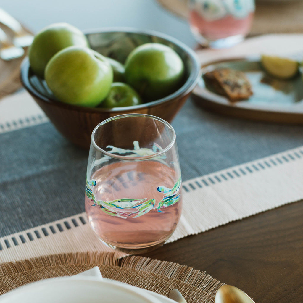 Table setting with a glass of pink lemonade, apples, and a bowl of cookies.