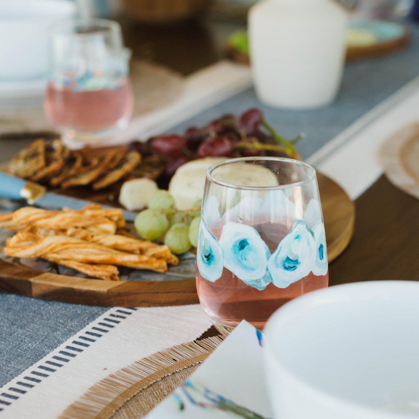 Dining table setting with wine glasses, plates, and appetizers on a tablecloth.