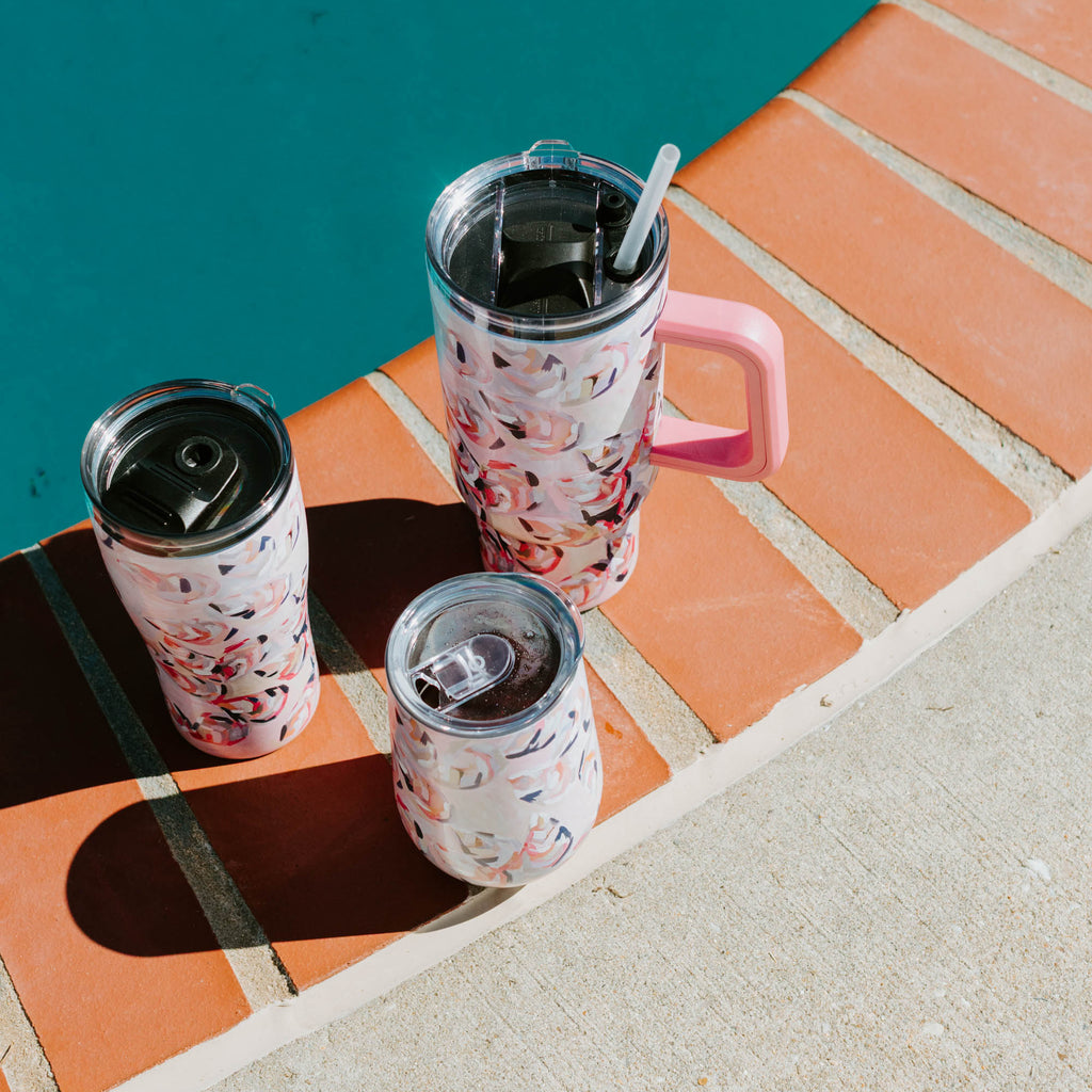 Three pink shell-patterned tumblers on a ledge by a pool.