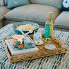 Tray with popcorn, wine, and Kim Hovell oyster pattern coaster on a coffee table in a living room.