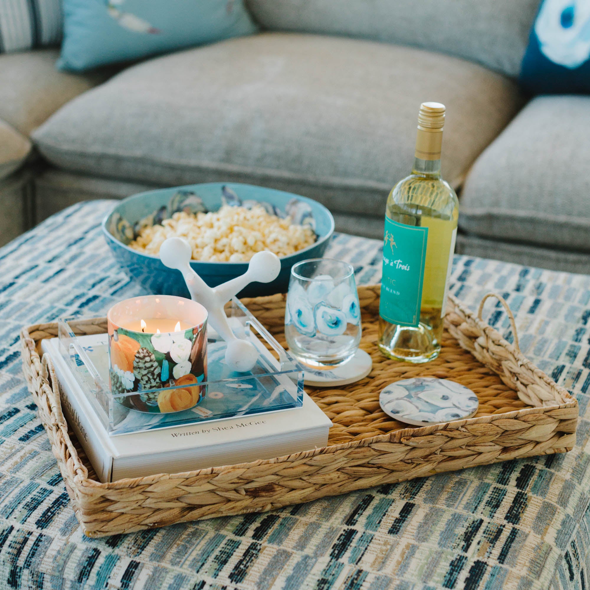Tray with popcorn, wine, and Kim Hovell oyster pattern coaster on a coffee table in a living room.