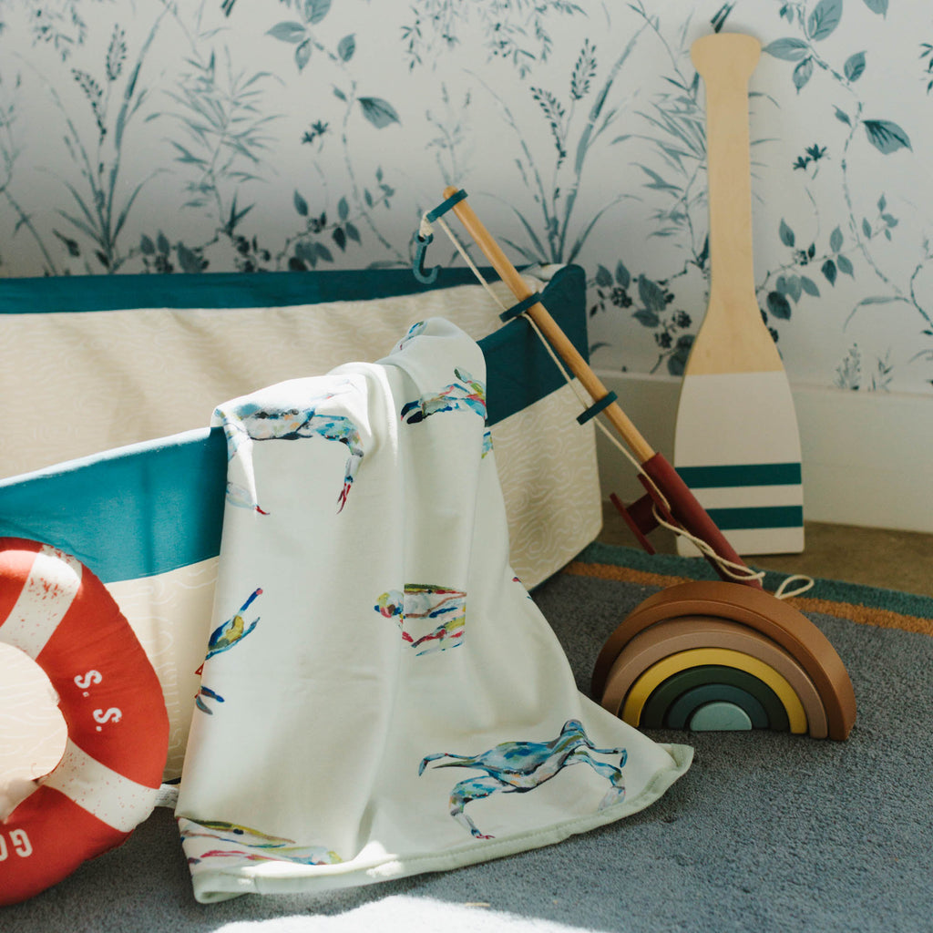 Children's room with floral wallpaper, toy sailboat, life buoy, and wooden oars.