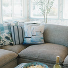 Living room with a sectional sofa, sailboat pillows, a bowl of popcorn, and a bottle of wine.
