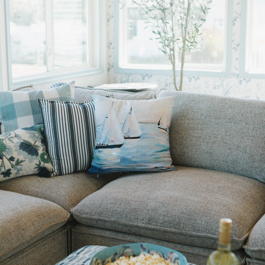 Living room with a sectional sofa, sailboat pillows, a bowl of popcorn, and a bottle of wine.