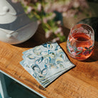 Glass of pink drink with floral design on a wooden table with floral background