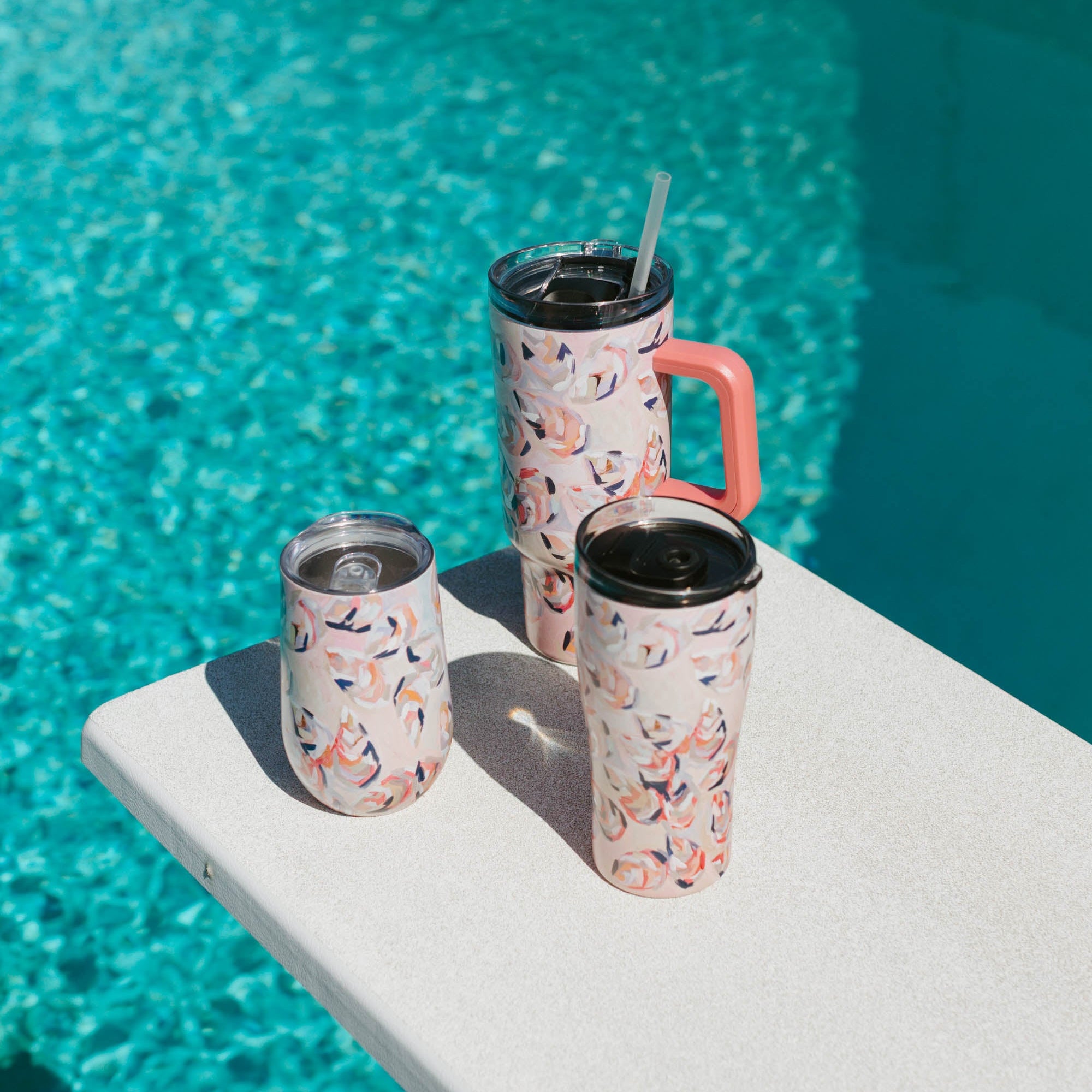 Three Kim Hovell Peach Gems pink shell-patterned tumblers on a pool diving board