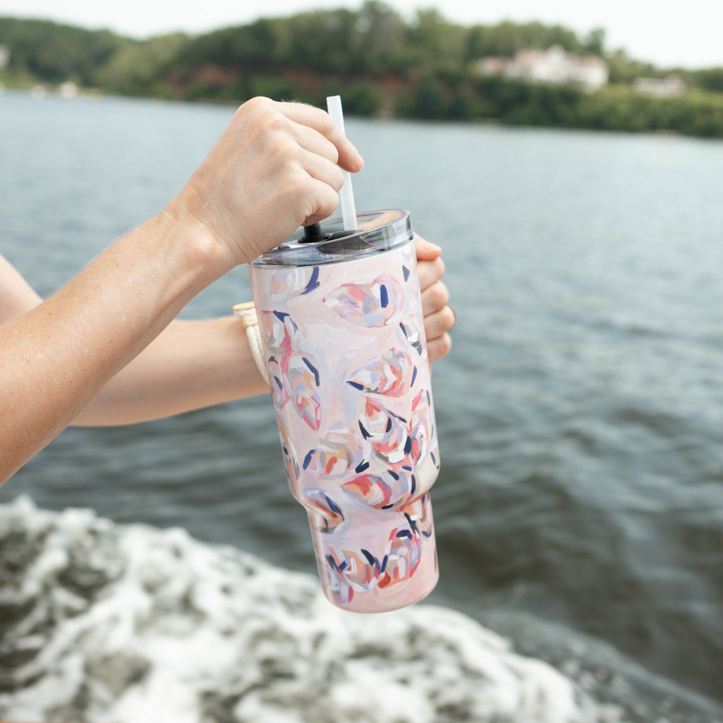 Person on a boat holding Kim Hovell Peach Gems Tumbler with lid and straw