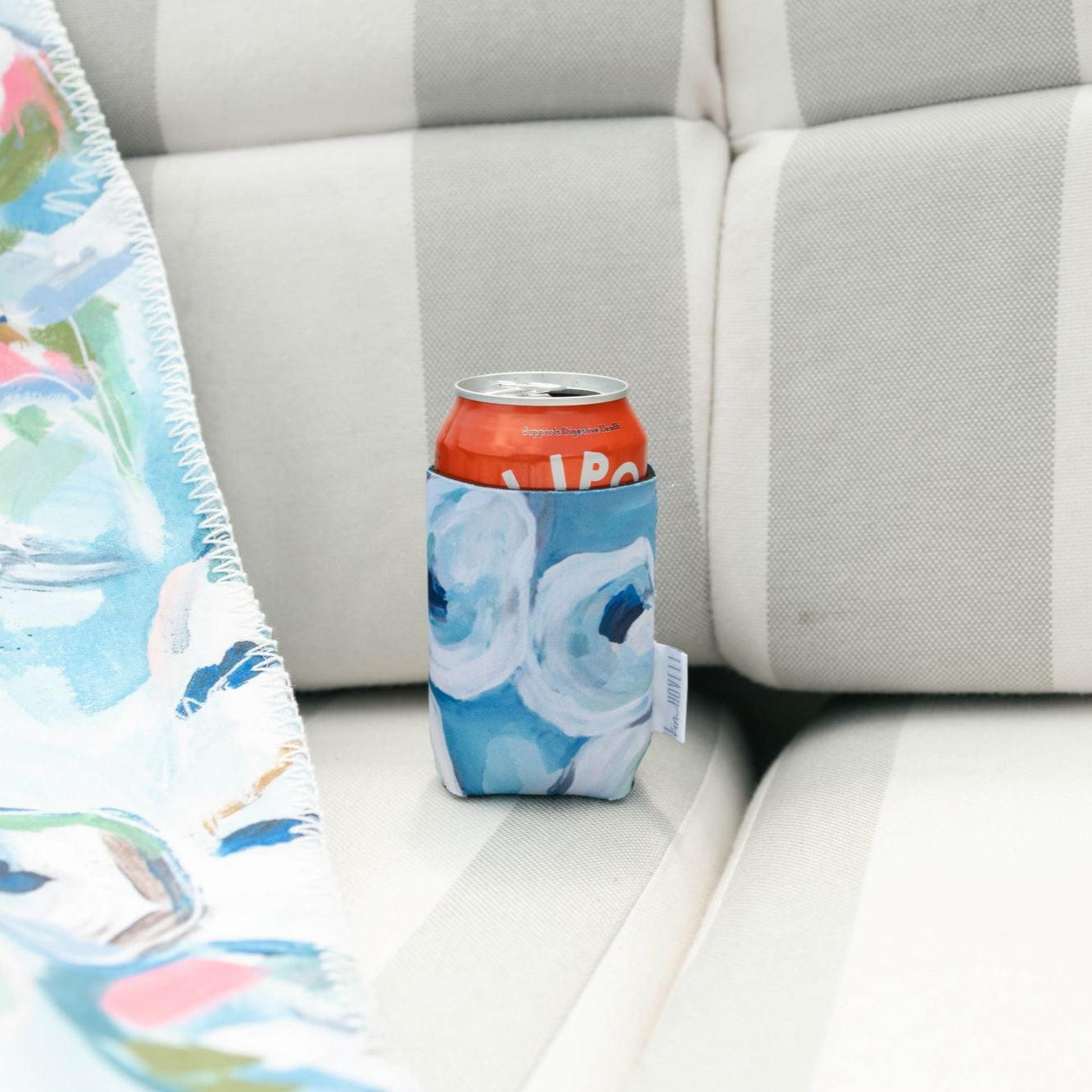 A red soda can in a Kim hovell koozie with a blue and white oyster pattern.