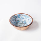 A medium-sized acacia wooden bowl with blue and white oyster patterned interior designed by Kim Hovell, placed against a white background.