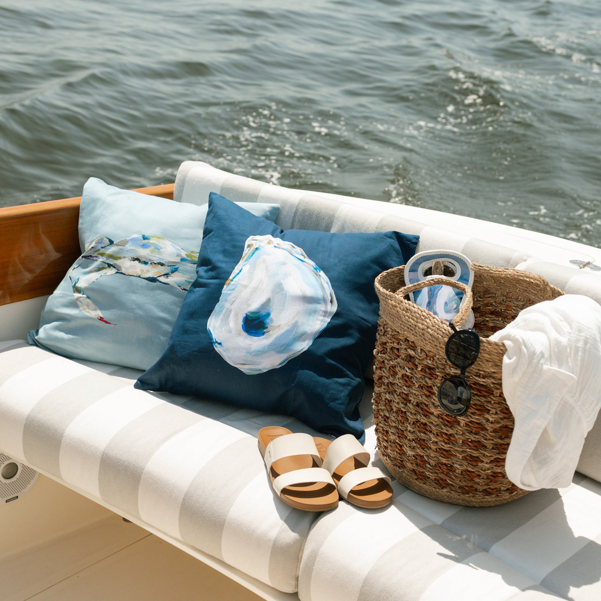 Chair with cushions, a basket, and sandals on a boat with water in the background