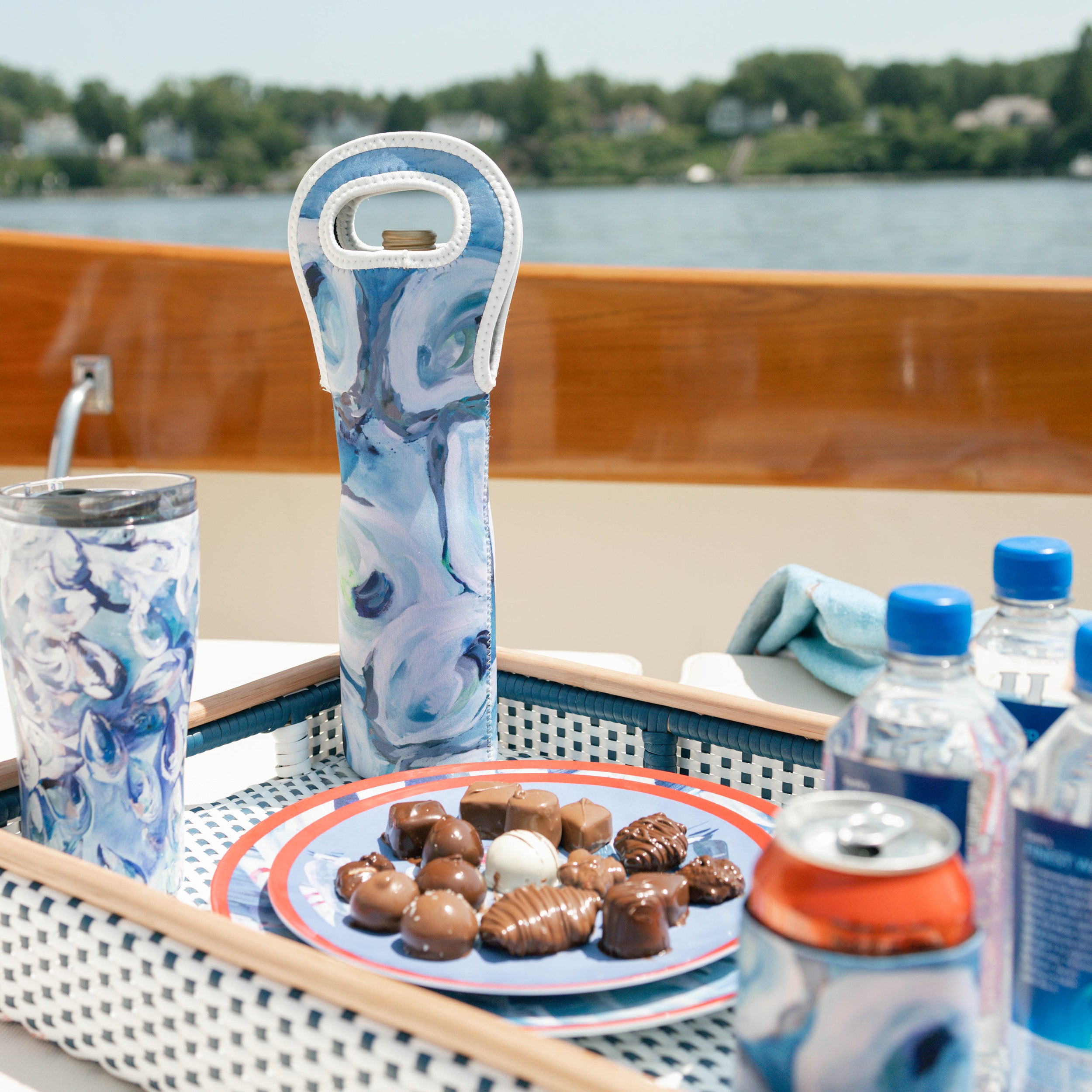 Kim Hovell blue and white oyster patterned wine tote bag with bottle inside on a table with snacks and drinks on a boat.