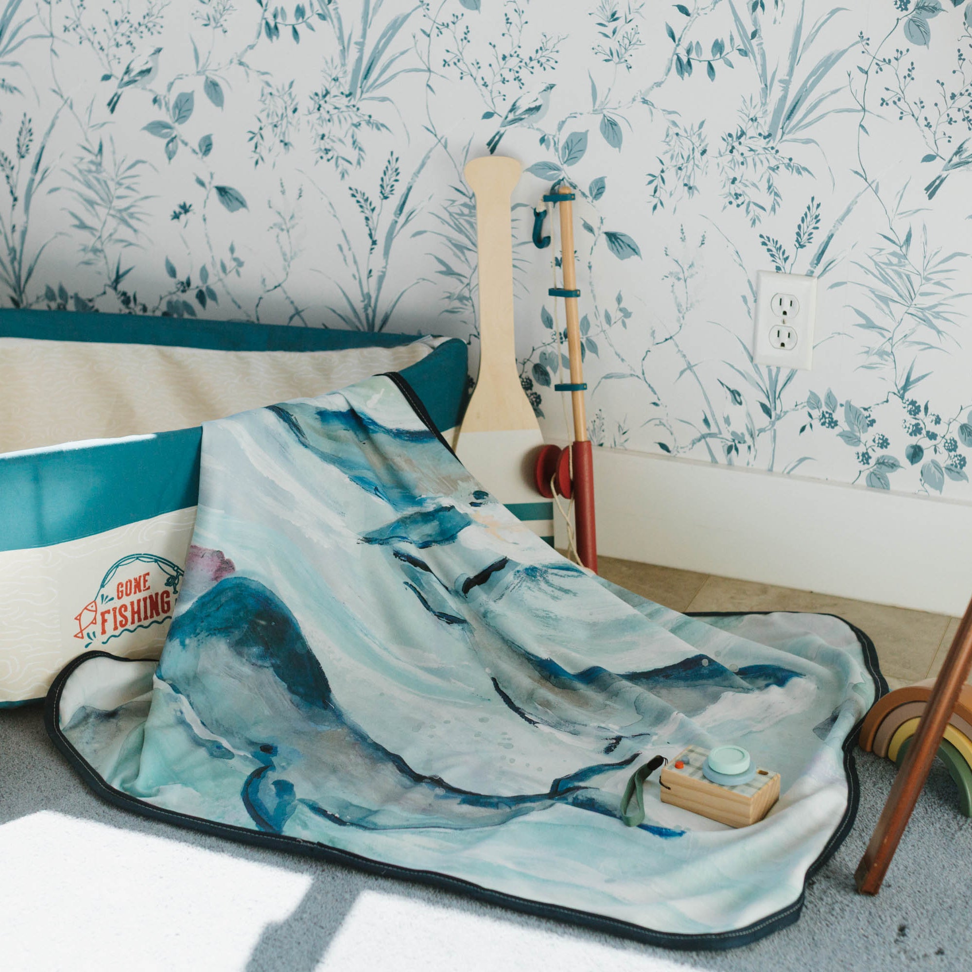 Children's play room with a blue and white whale baby blanket draped over boat play set